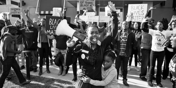 african-american protestors hold signs and a megaphone