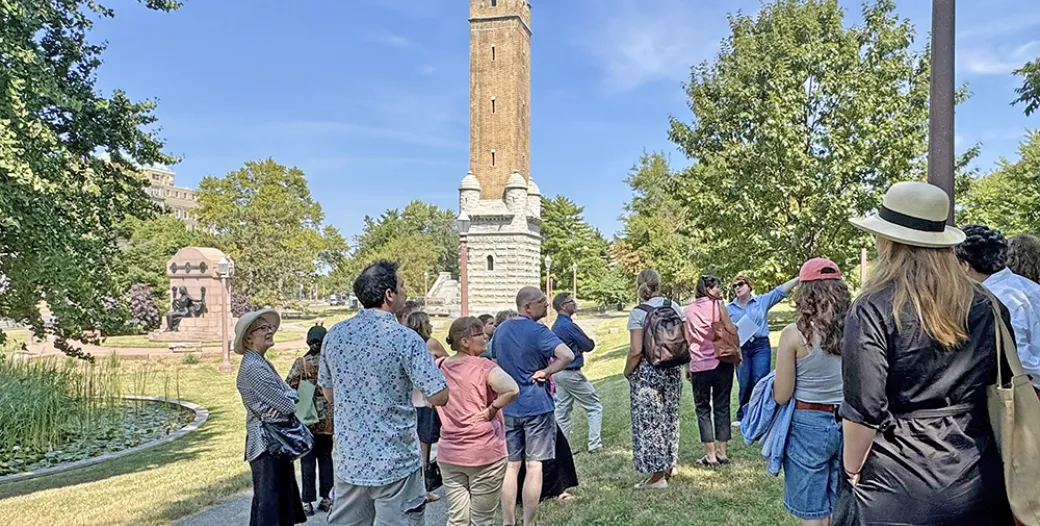"A group of people in an outdoor setting with a brick water tower in the background"
