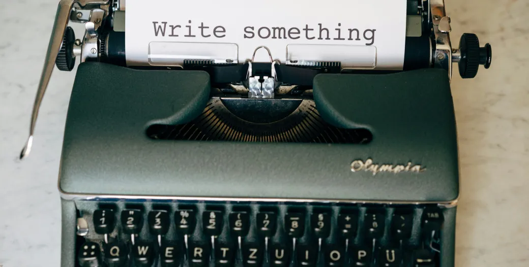 Image displays a typewriter with a sheet of paper that says "Write something."