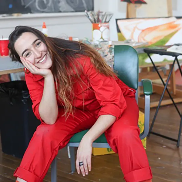 "woman wearing a red jumpsuit in an art studio setting"