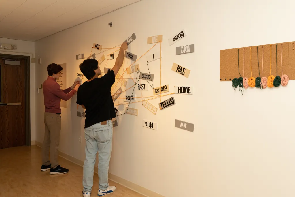 Participants use yarn to string together words posted on the wall, telling their own story, at the COCA exhibit.