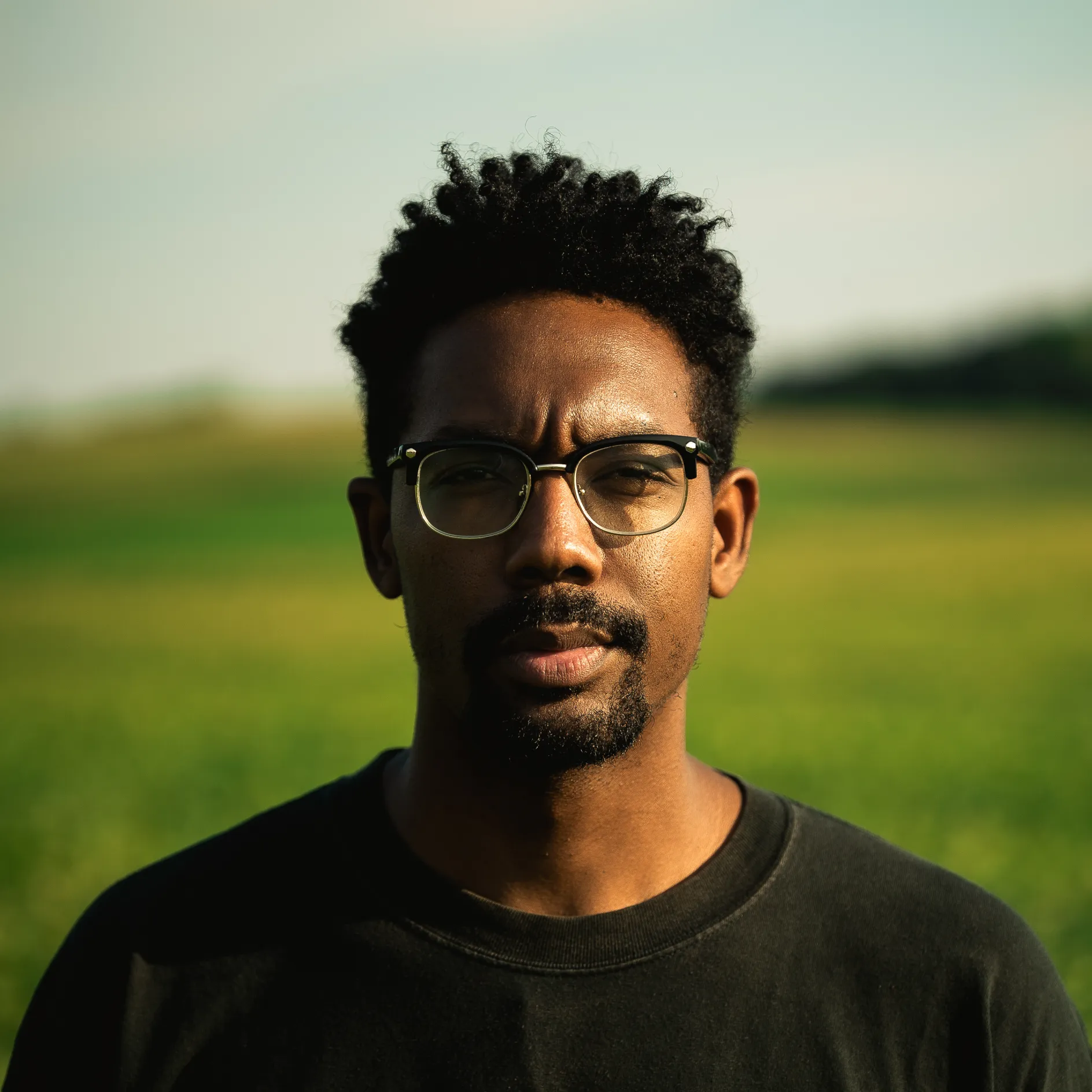"a man in a black shirt standing in an outdoor setting"