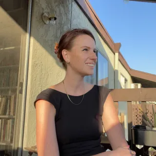 "Headshot of a woman in a black top sitting in an outdoor setting"