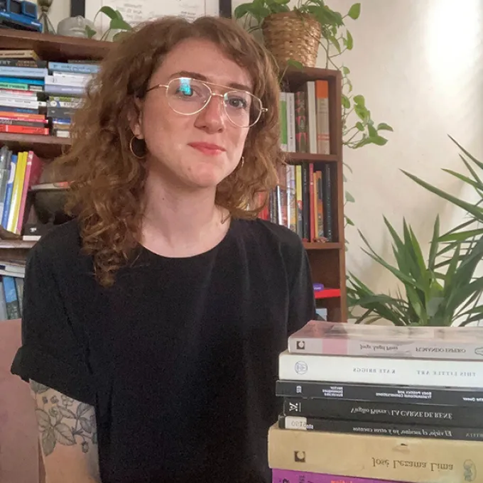 "woman in a black t-shirt sitting among stacks of books"