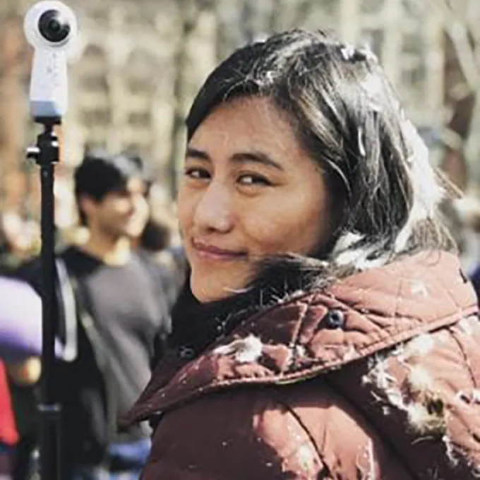 "woman wearing a brown coat behind filming equipment"