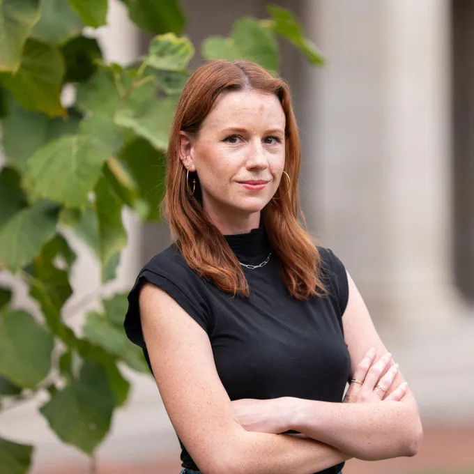 "woman wearing a black shirt standing near a tree"